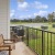 a balcony with chairs and a table on it by a grass field