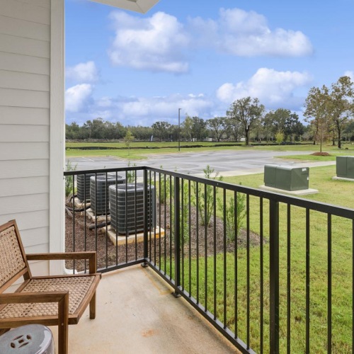 Spacious balconies a balcony with chairs and a table on it by a grass field